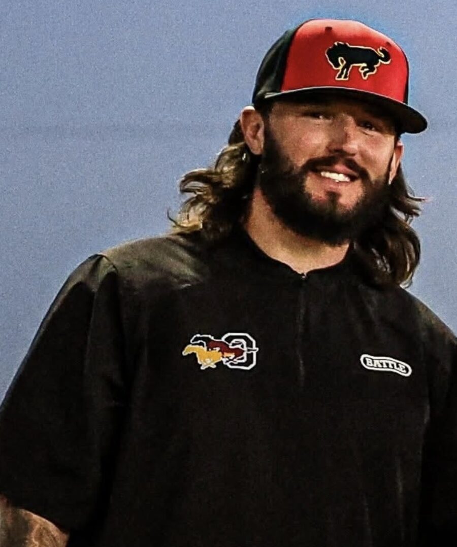 Coach Corey Keller in a Kellz Camp cap, smiling on the field