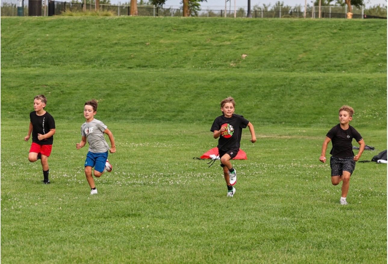 Young athletes sprinting across the field with a football