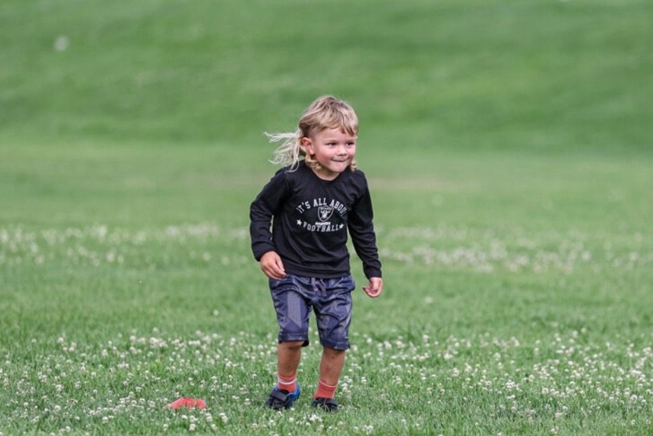 A young camper smiling mid-run on the field